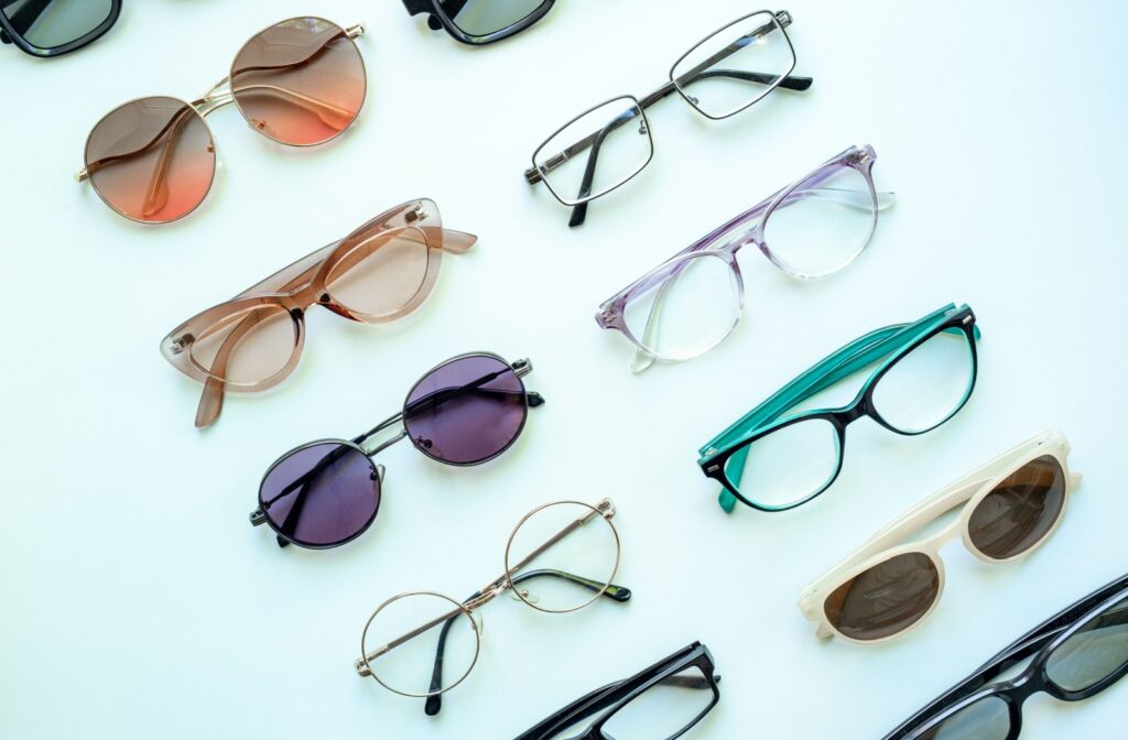 A variety of trendy eyeglasses and sunglasses sitting on a white counter at an eye doctor's office.