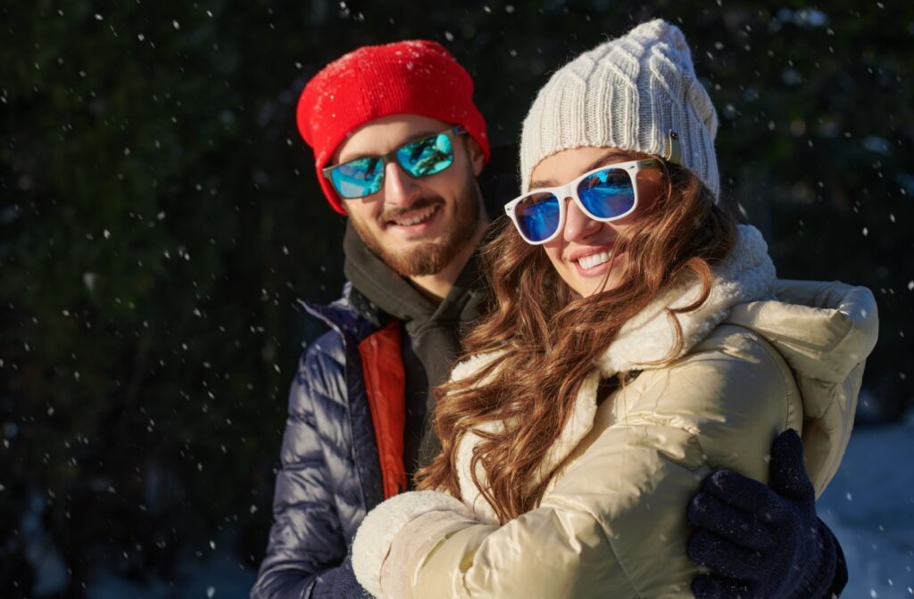 A couple wearing sunglasses while walking together in the snow.